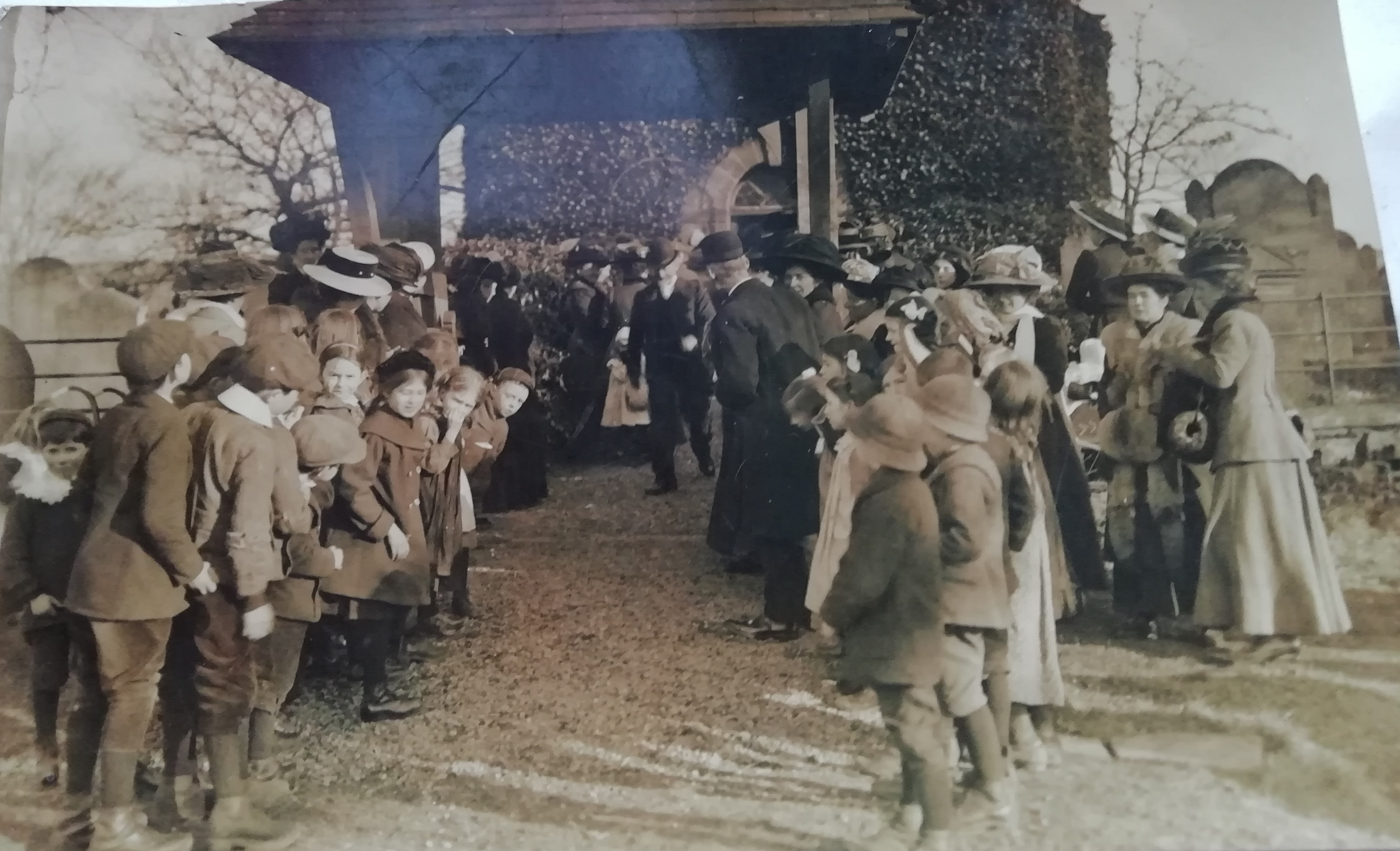 Black and white photograph of wedding party by lychgate. 1911.